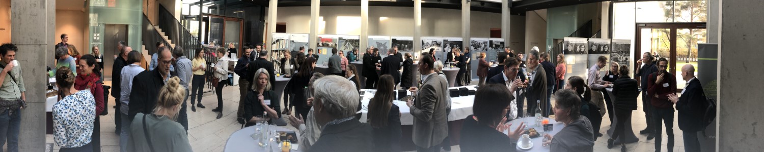 Panoramaaufnahme des Foyers mit vielen Teilnehmern, die miteinander diskutieren.